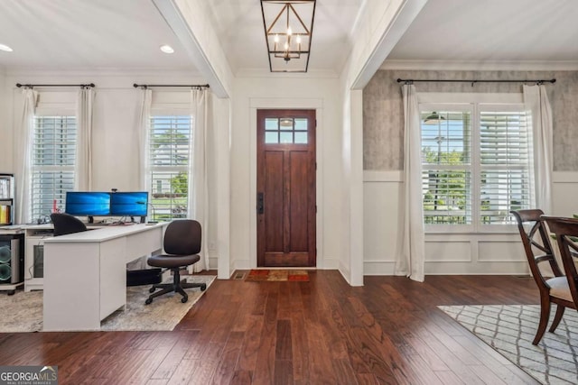 foyer with a wealth of natural light, wood-type flooring, crown molding, and an inviting chandelier