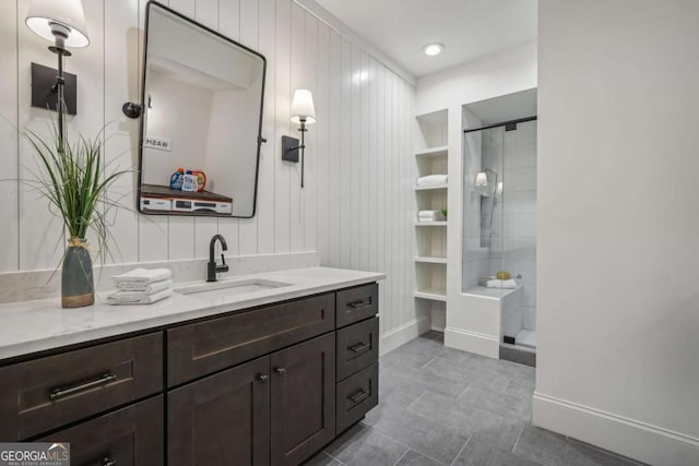 bathroom with a stall shower, vanity, and baseboards