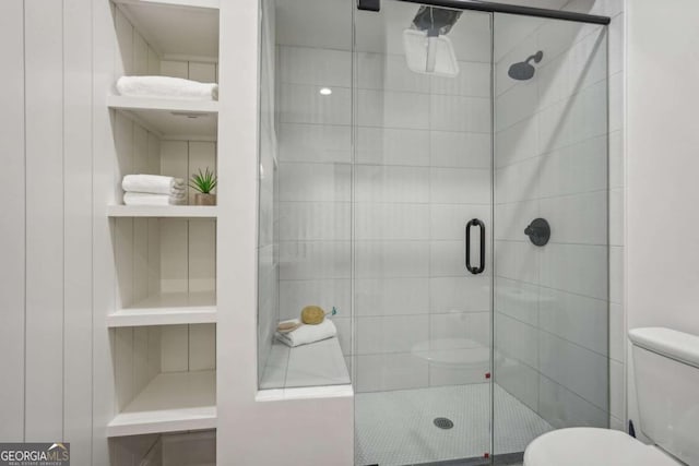 bathroom featuring built in features, a shower stall, and toilet