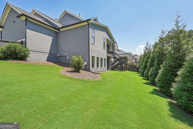 view of side of home featuring stairway and a lawn