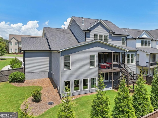 back of property with a shingled roof, fence, stairway, and a yard