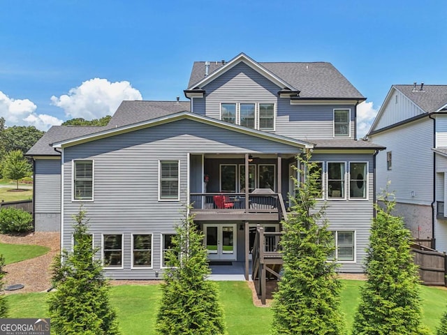 rear view of property featuring a balcony, roof with shingles, french doors, and a yard