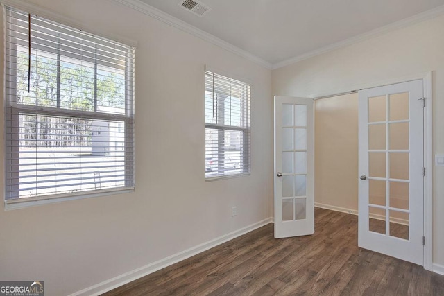 empty room featuring french doors, crown molding, visible vents, wood finished floors, and baseboards