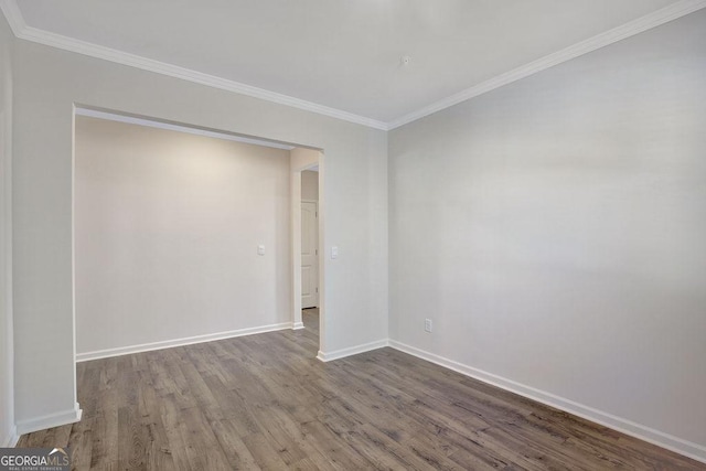 empty room featuring crown molding, wood finished floors, and baseboards