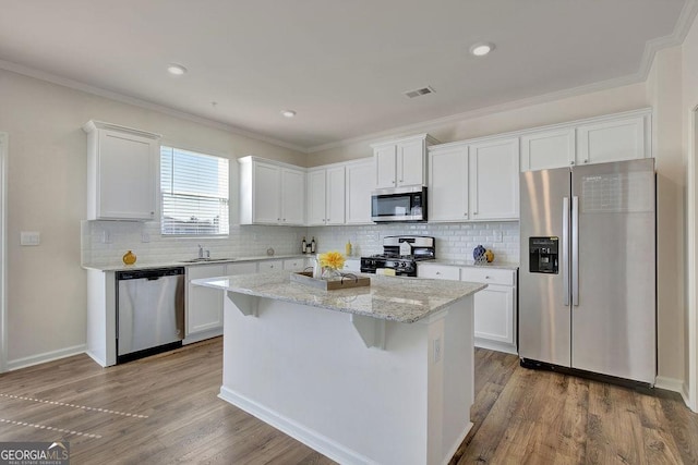 kitchen featuring visible vents, appliances with stainless steel finishes, white cabinets, a sink, and wood finished floors