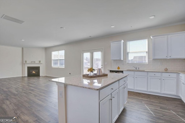 kitchen featuring dark wood-style flooring, visible vents, a kitchen island, and a lit fireplace