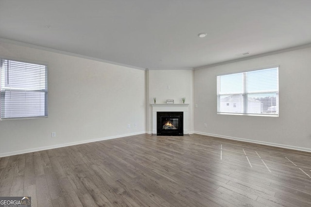 unfurnished living room featuring a glass covered fireplace, crown molding, and wood finished floors