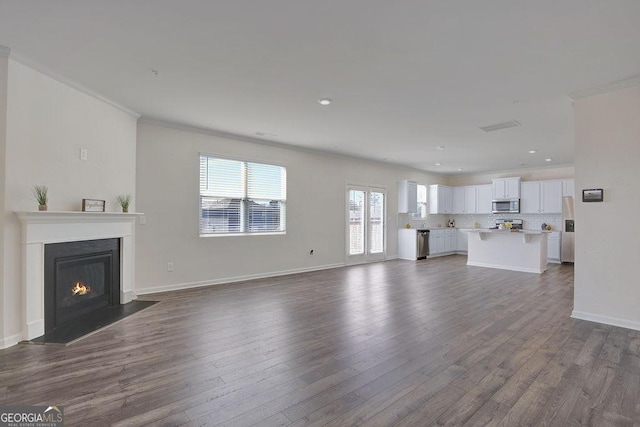 unfurnished living room featuring dark wood-style floors, a fireplace with flush hearth, and baseboards