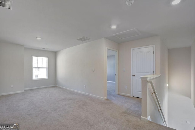 empty room featuring light carpet, baseboards, visible vents, and attic access