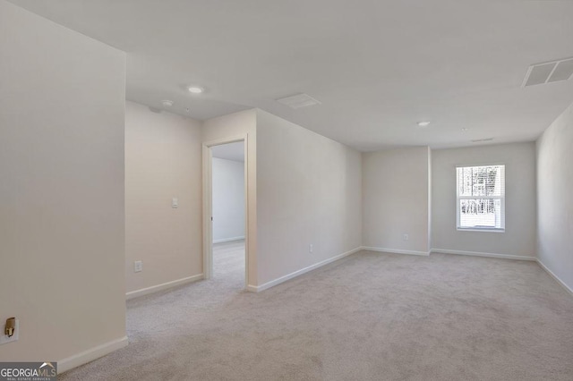 empty room with carpet floors, visible vents, and baseboards