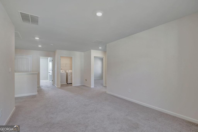 unfurnished room featuring recessed lighting, visible vents, attic access, washing machine and dryer, and light carpet