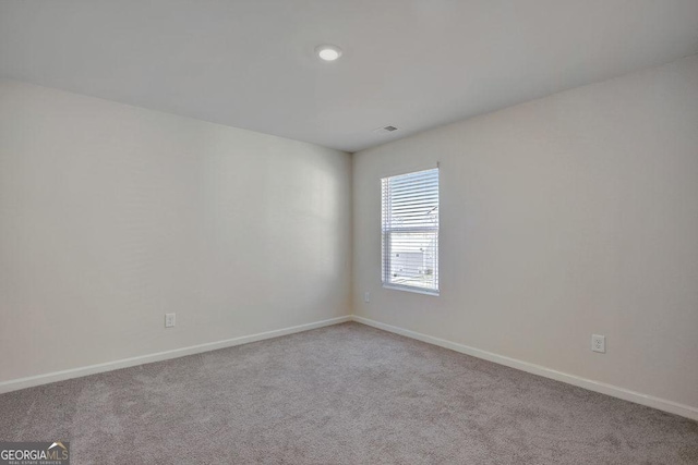 carpeted spare room featuring visible vents and baseboards