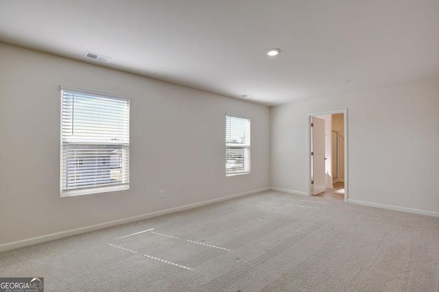 empty room with light carpet, visible vents, and baseboards