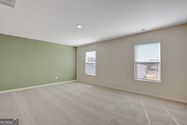 unfurnished room with light colored carpet, visible vents, and baseboards