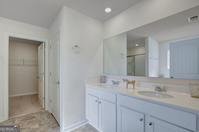 full bath with visible vents, a sink, a shower stall, and double vanity