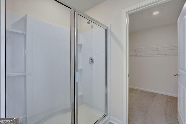 full bathroom featuring a stall shower, baseboards, and a walk in closet