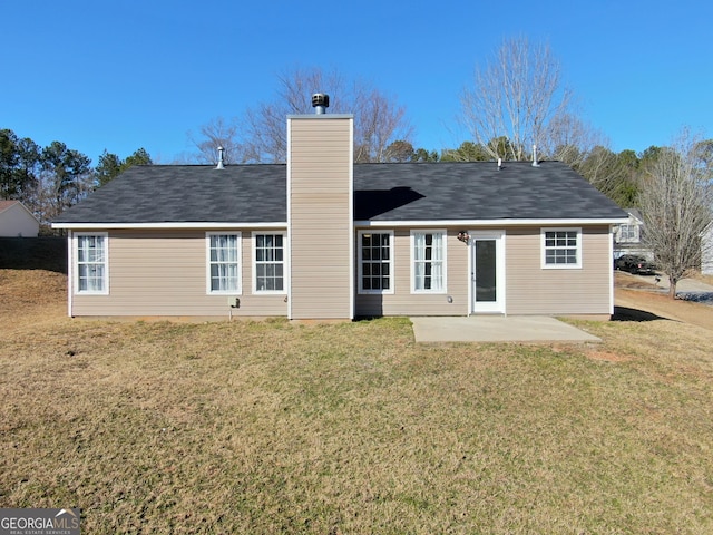 rear view of house featuring a patio area, a yard, and a chimney