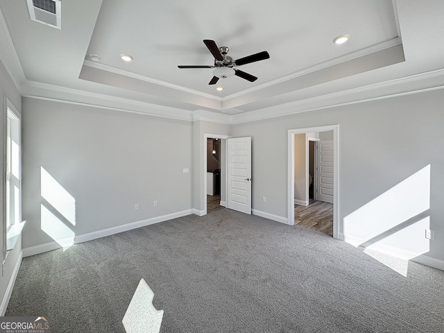 unfurnished bedroom with baseboards, visible vents, a tray ceiling, and carpet flooring