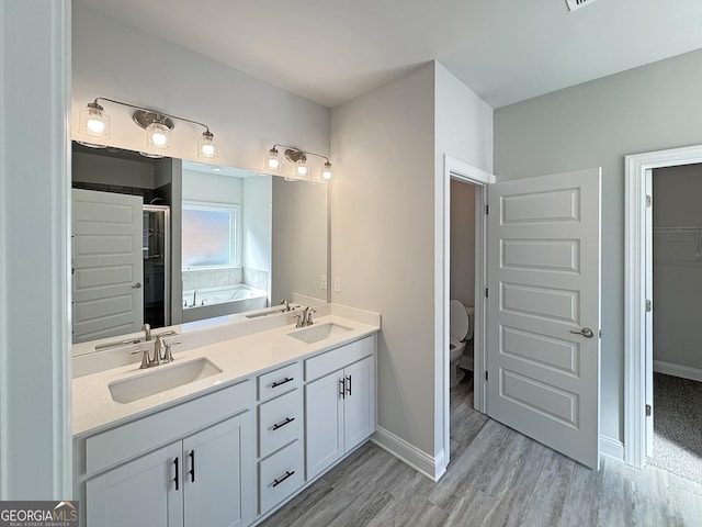 full bathroom with toilet, wood finished floors, a sink, and a bath