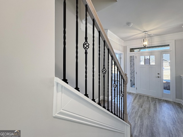 foyer with baseboards, stairway, ornamental molding, wood finished floors, and a notable chandelier