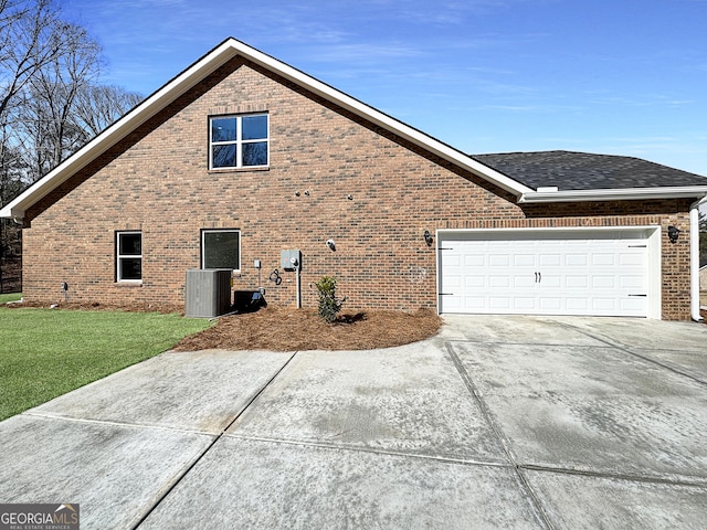 view of side of home featuring cooling unit, a garage, brick siding, a yard, and concrete driveway