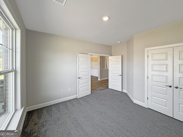 unfurnished bedroom featuring carpet, visible vents, baseboards, and a closet