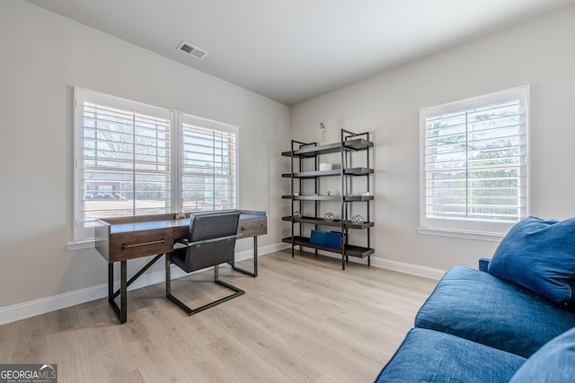 office area with light wood-type flooring, visible vents, and baseboards