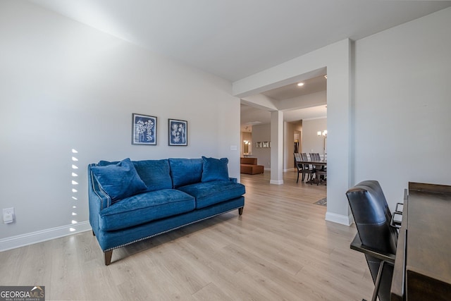 living room featuring light wood-type flooring, baseboards, and a notable chandelier