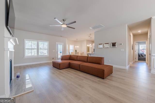 living area featuring light wood-style flooring, a fireplace, visible vents, and ceiling fan