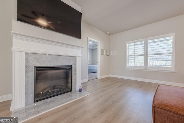 unfurnished living room with a fireplace, baseboards, and wood finished floors