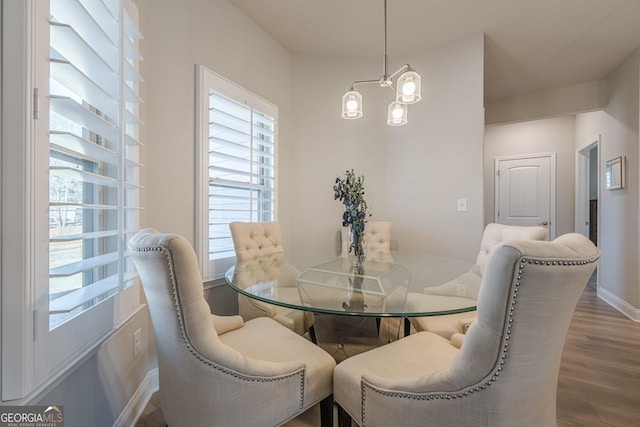 dining space with baseboards, an inviting chandelier, and wood finished floors