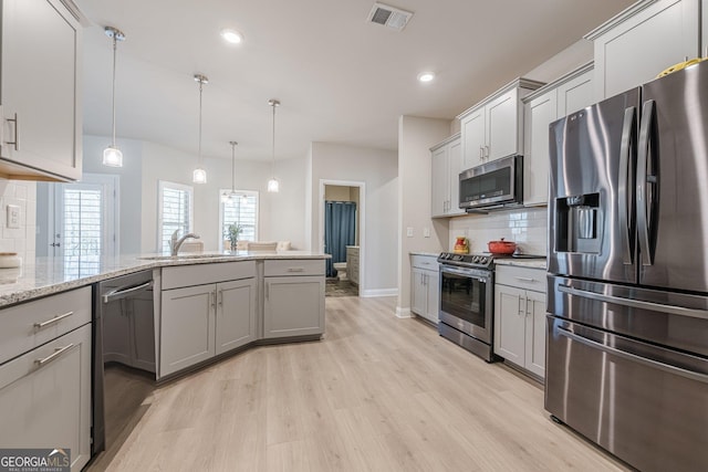 kitchen featuring visible vents, backsplash, appliances with stainless steel finishes, a sink, and light wood-type flooring