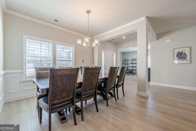 dining space featuring light wood finished floors, visible vents, a notable chandelier, and ornamental molding