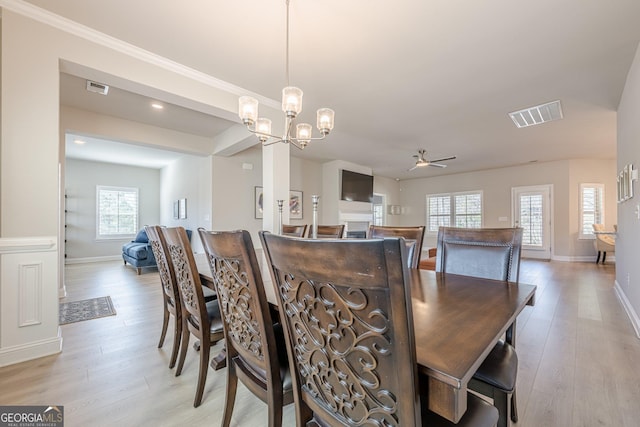 dining area with ceiling fan with notable chandelier, light wood-style flooring, visible vents, and baseboards