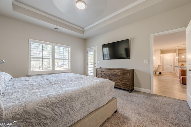 carpeted bedroom with ornamental molding, a tray ceiling, visible vents, and baseboards