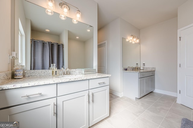 full bath with tile patterned floors, two vanities, a sink, and baseboards