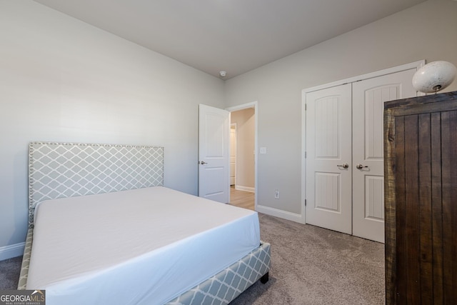 bedroom featuring a closet, light colored carpet, and baseboards