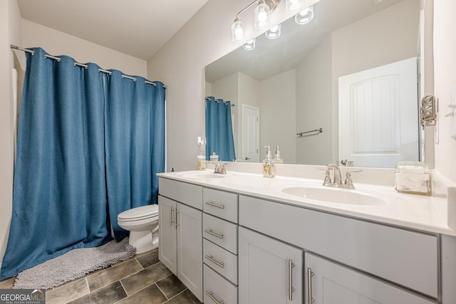 full bath featuring double vanity, a sink, and toilet