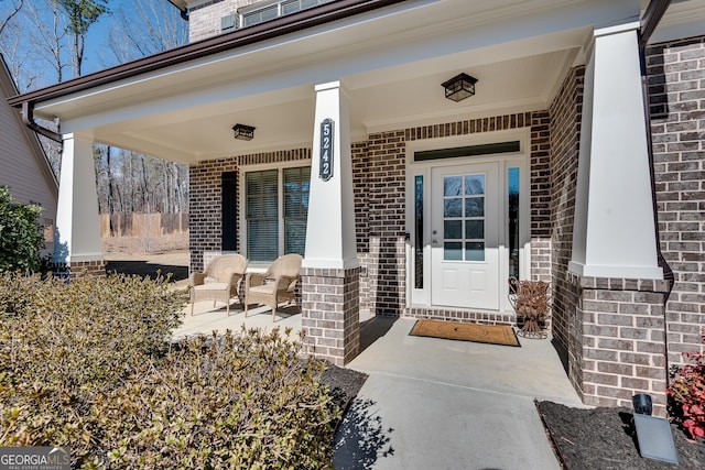 property entrance featuring covered porch and brick siding