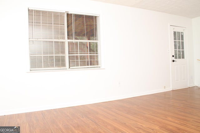 unfurnished room featuring a textured ceiling, baseboards, and wood finished floors