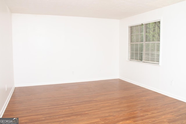 unfurnished room with baseboards and wood finished floors