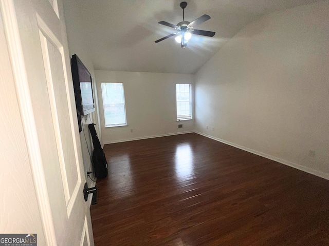 interior space featuring lofted ceiling, visible vents, dark wood-type flooring, a ceiling fan, and baseboards