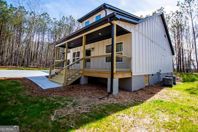 view of front of home featuring a porch, board and batten siding, a front lawn, and central air condition unit