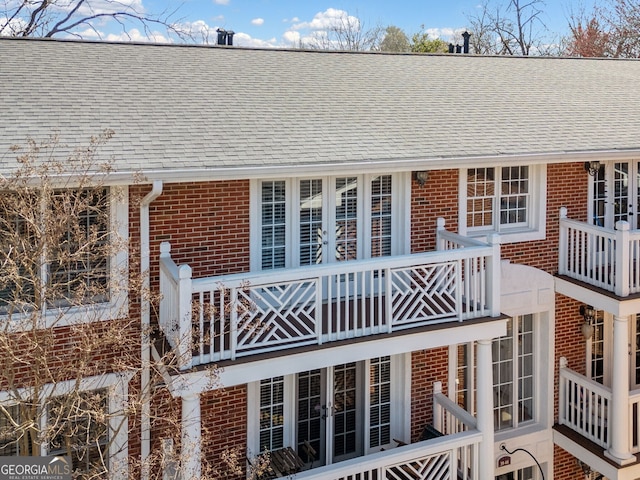 back of property featuring a shingled roof, french doors, and brick siding