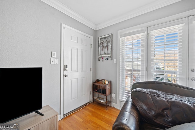 entryway with ornamental molding and light wood-style floors