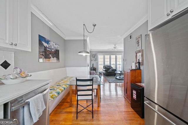 kitchen featuring crown molding, visible vents, freestanding refrigerator, white cabinetry, and light wood-type flooring