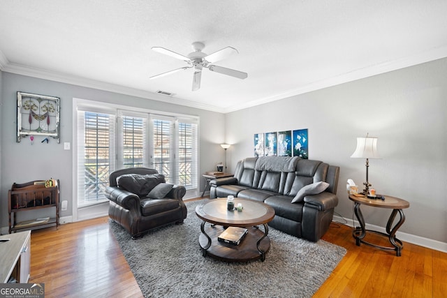 living area with crown molding, baseboards, visible vents, and light wood-style floors