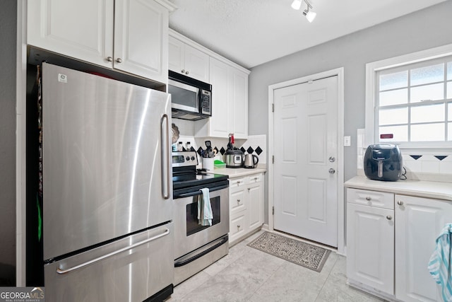 kitchen with stainless steel appliances, light countertops, white cabinetry, and decorative backsplash