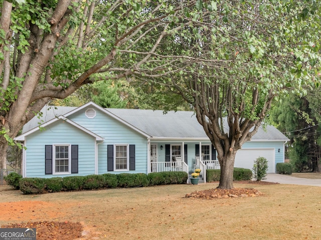 ranch-style home featuring an attached garage, a porch, concrete driveway, and a front yard