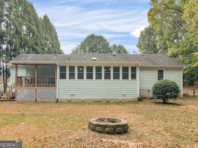 rear view of property with an outdoor fire pit and a yard